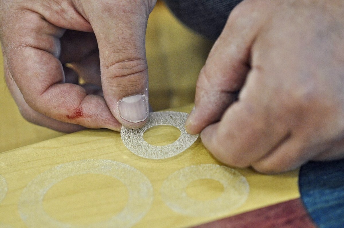 Mains appliquant du grip tape sur un plateau de skateboard