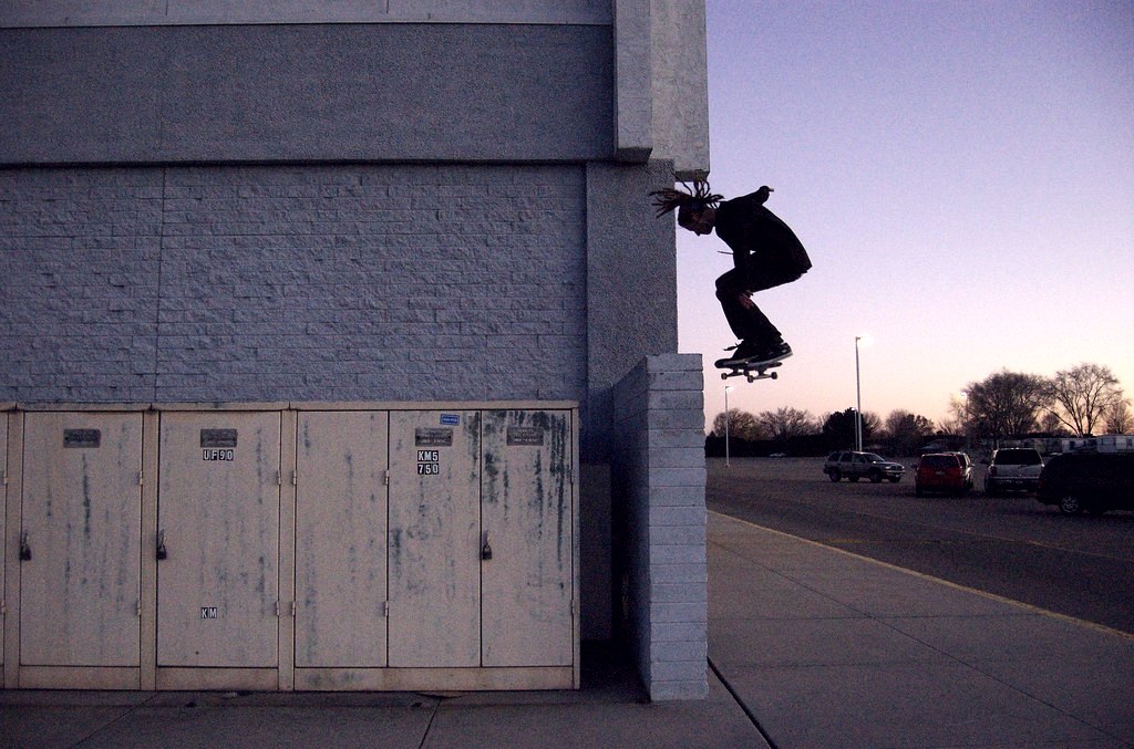 Skateur en 180 au crépuscule, ambiance urbaine nocturne — évocation de la vitesse et du contrôle