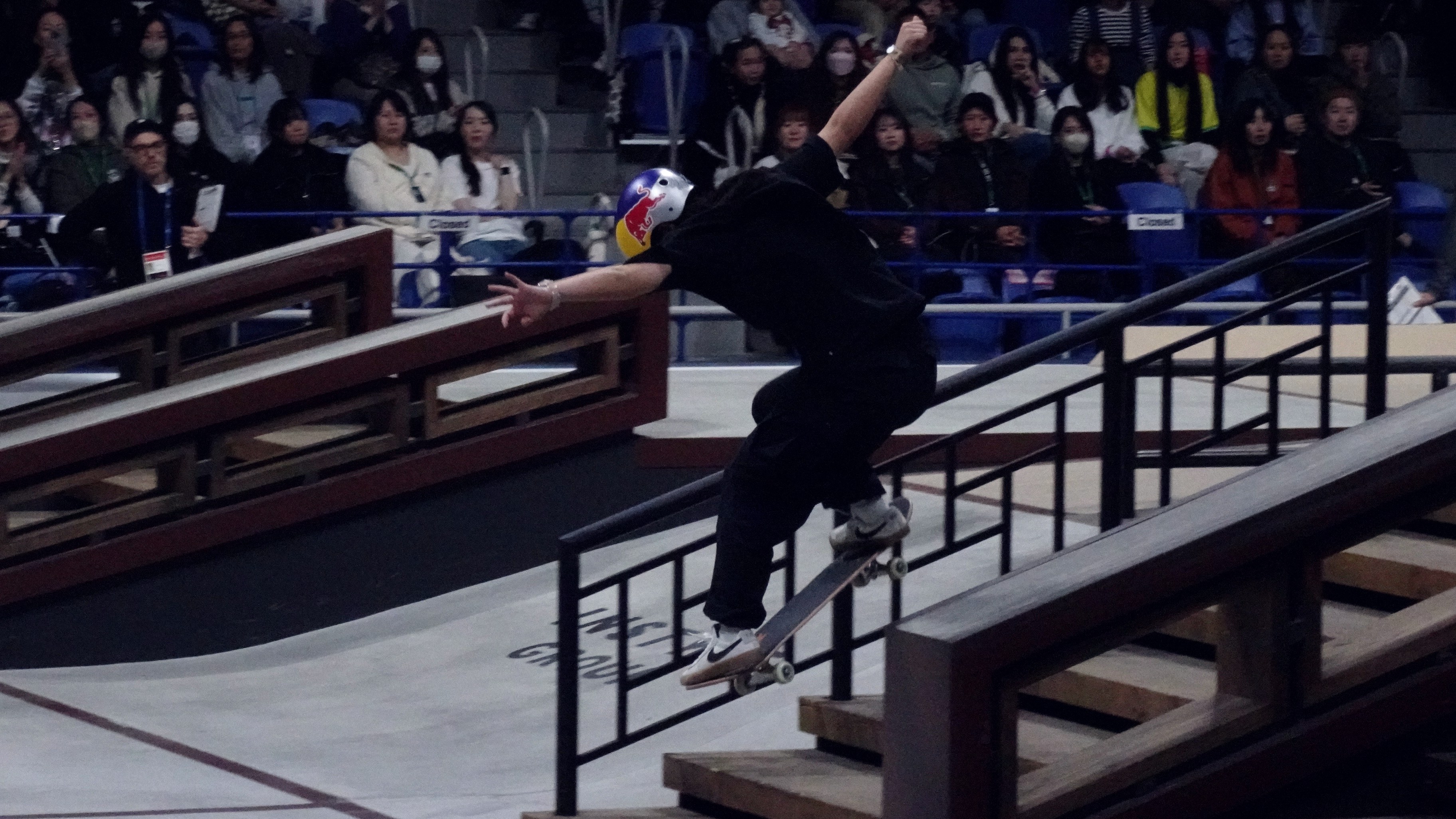 Skateur en lipslide sur un handrail lors d'une finale street indoor devant le public