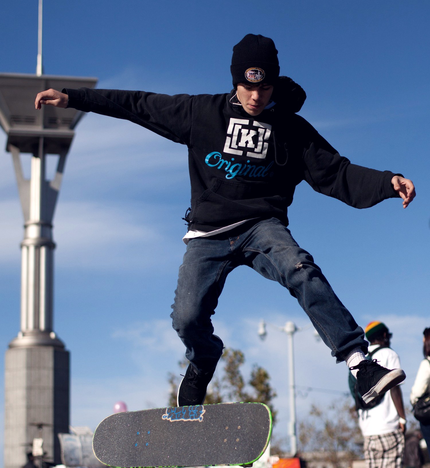 Skateur en pleine rotation de kickflip sur une place urbaine, planche décollée sous les pieds