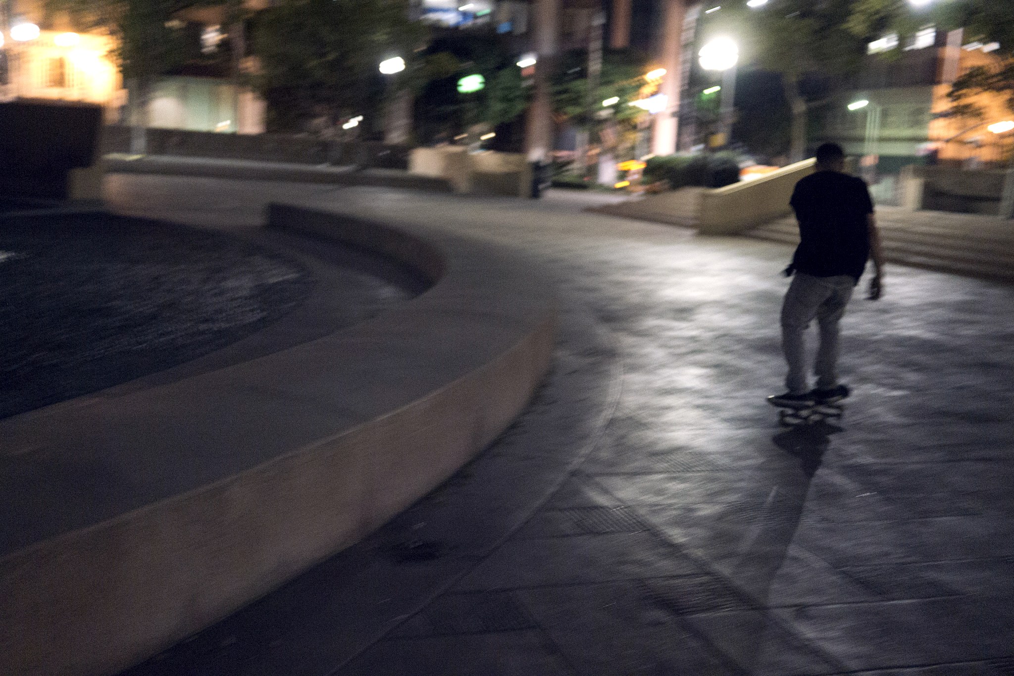Skateur roulant de nuit sur une plaza en béton du centre de Los Angeles