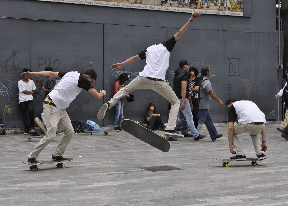 Skateur en plein flip trick, planche en rotation sous les pieds — mécanique du heelflip