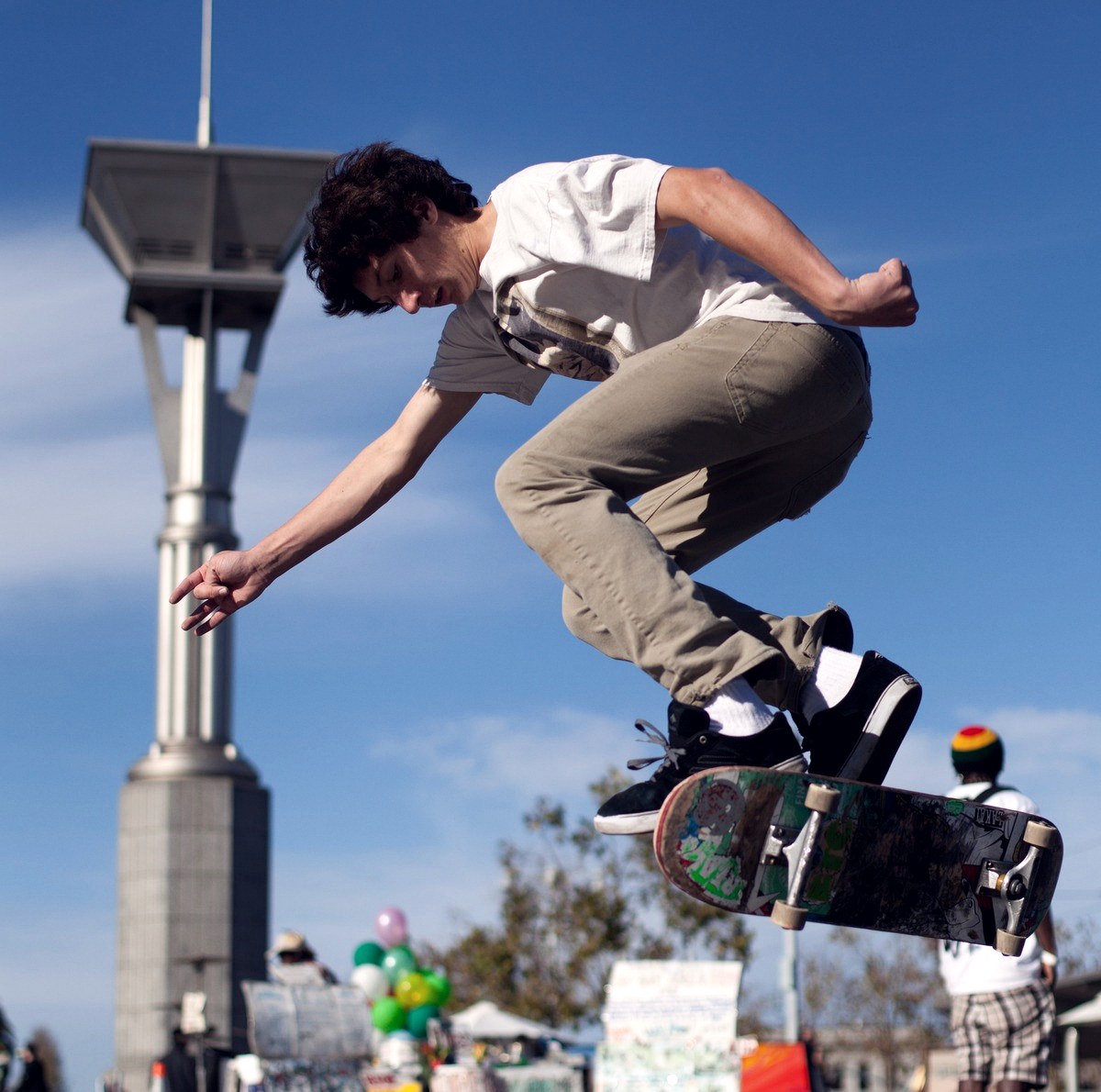 Skateur rattrapant sa planche du pied arrière en fin de flip, place de l'Embarcadero à San Francisco