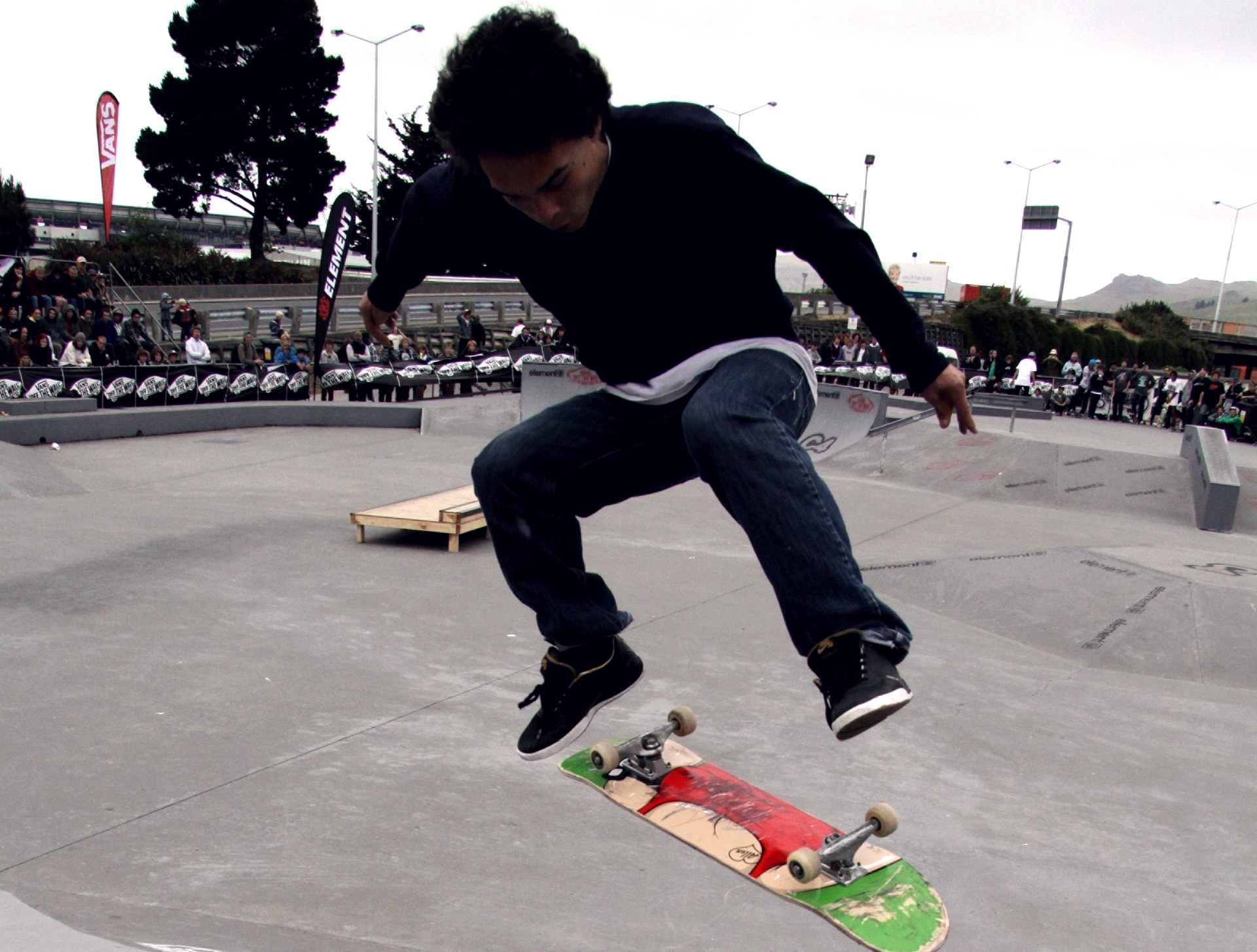 Skateur en plein backside flip en contest : le corps entame la rotation pendant que la planche flippe sous ses pieds