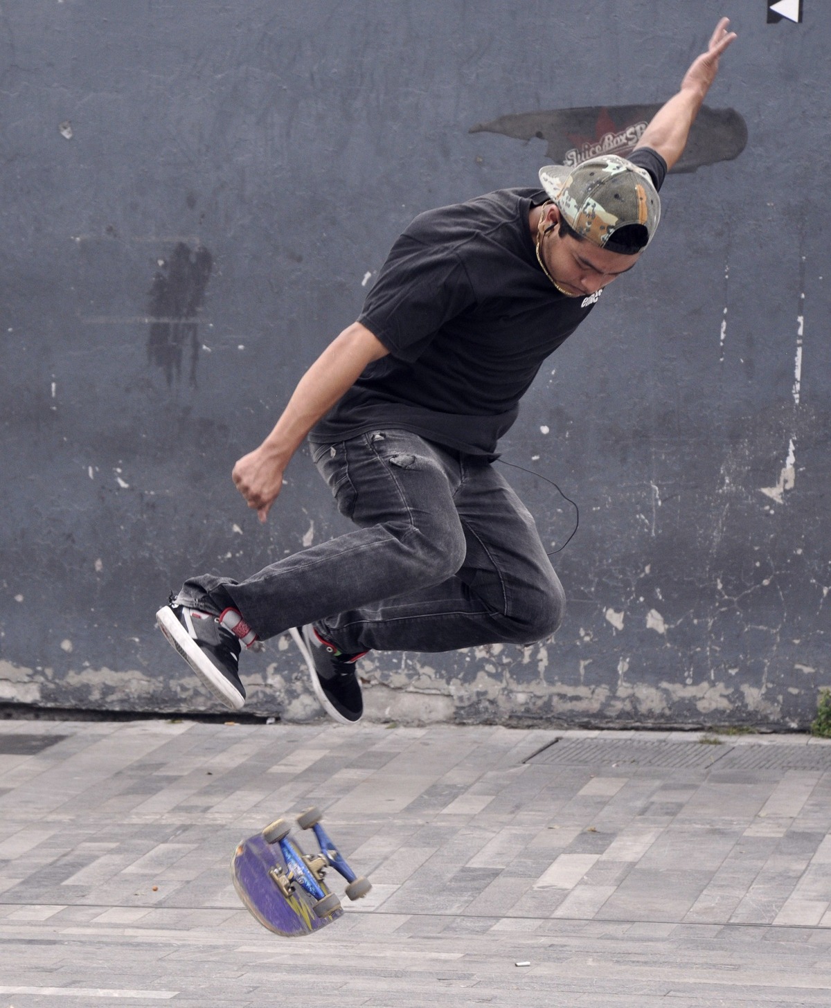Vue rapprochée d'un flip de rue : la planche tourne toute seule sous le skateur, pieds décollés, juste avant le catch