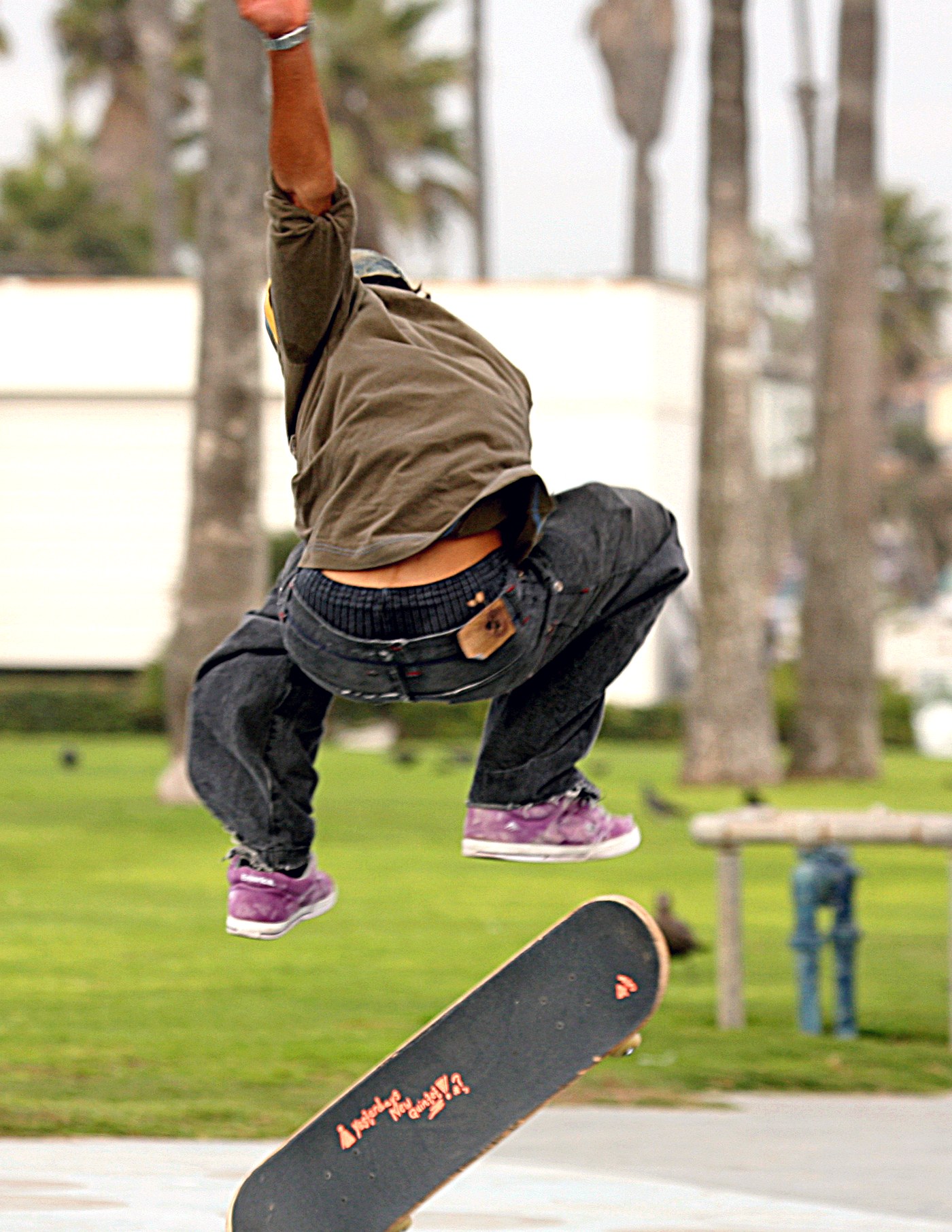 Skateur en plein kickflip, chaussures et planche en l'air dans un skatepark