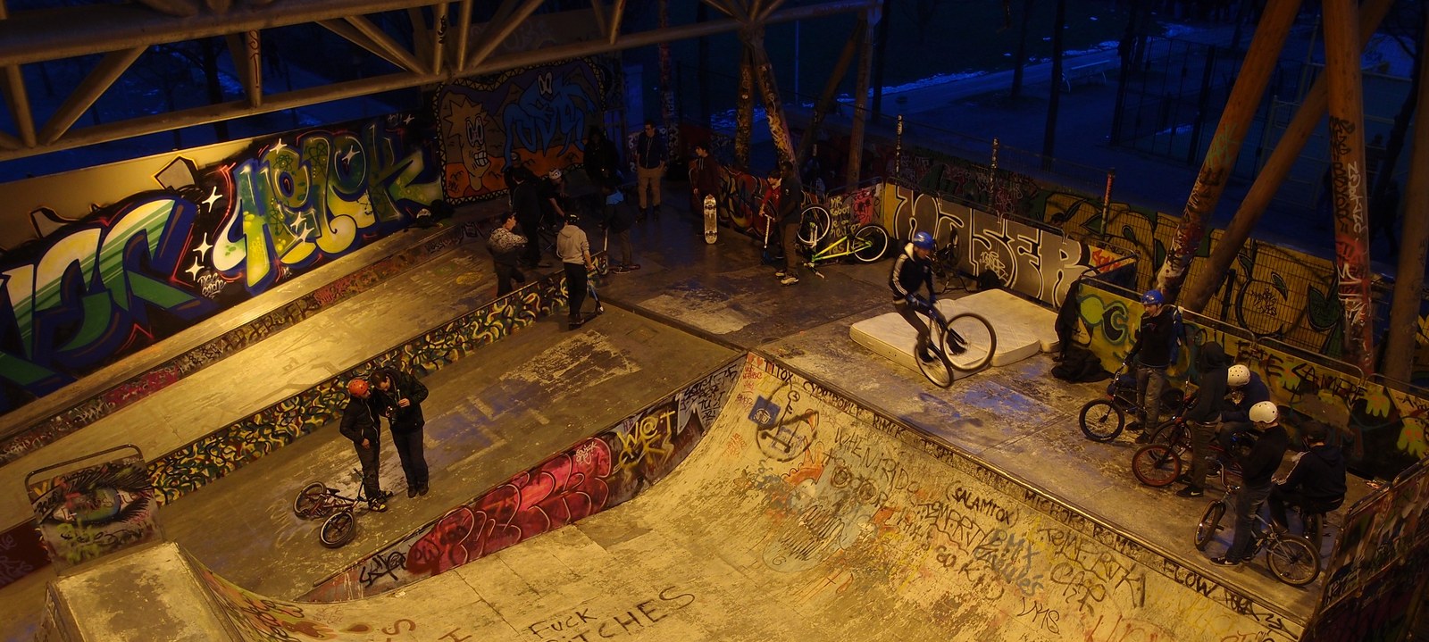 Le skatepark couvert de Bercy à Paris en soirée, quarters en béton et riders sur la plateforme