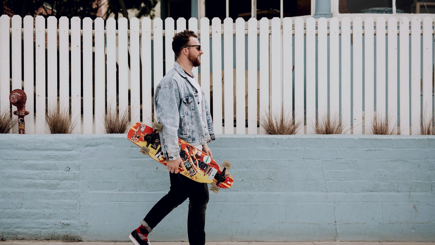 Skateur marchant sur un trottoir avec sa planche tenue à la main