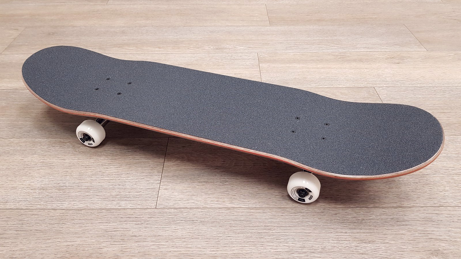 Skate complet monté vu du dessus, grip neuf, roues blanches — l'assemblage à 217 euros