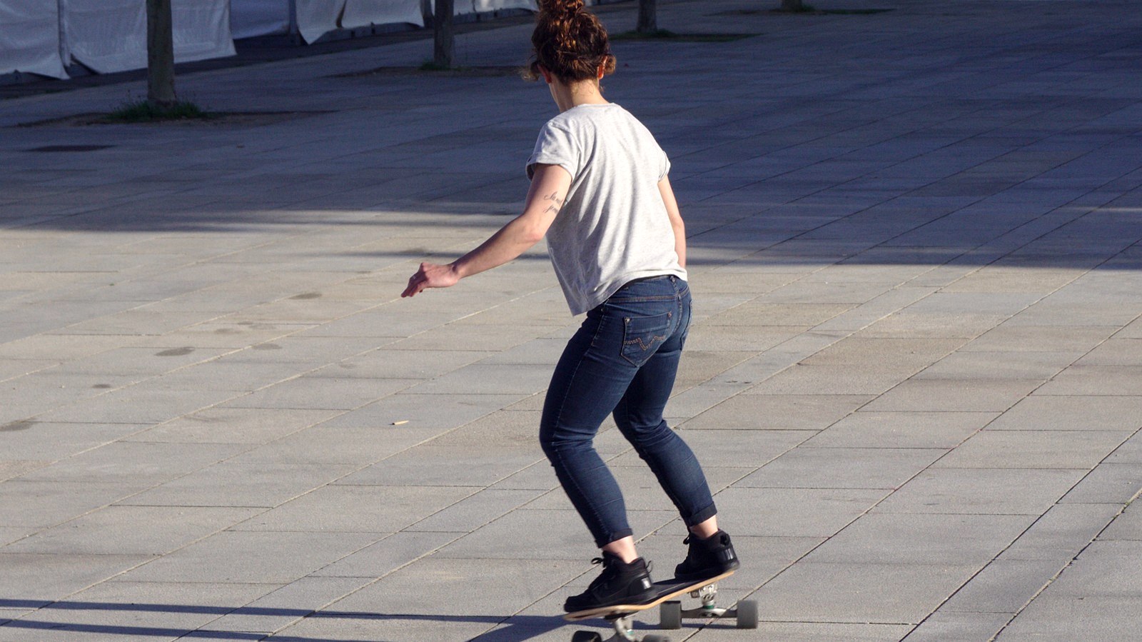 Skateuse poussant son skate dans la rue en France : en euros comparables ce skate reste moins cher qu'en 2005