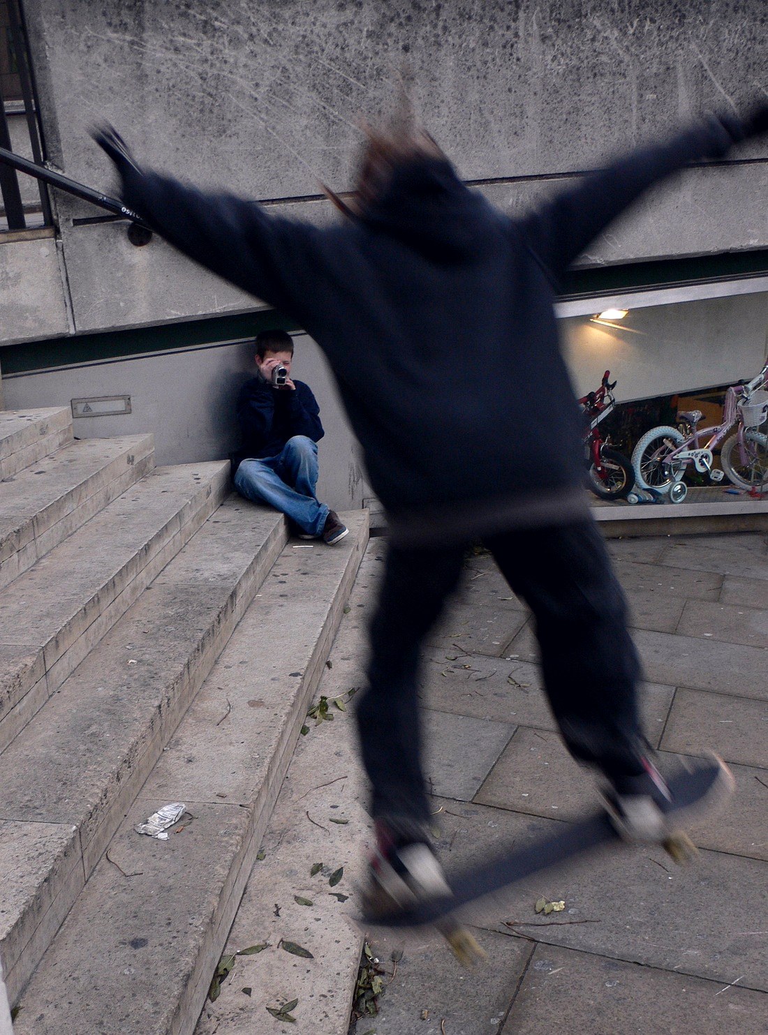 Un skateur filmé par un ami pendant qu'il saute un escalier de rue