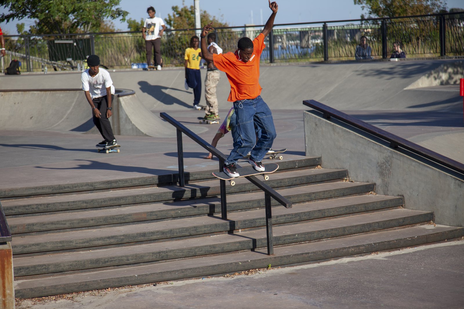 Best trick : un skateur verrouille un boardslide sur le rail d'un escalier, bras écartés