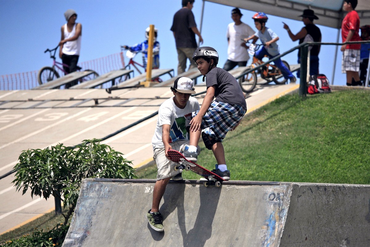 Jeune skateur casqué prêt à dropper, aidé par un plus grand : le casque fait partie du budget