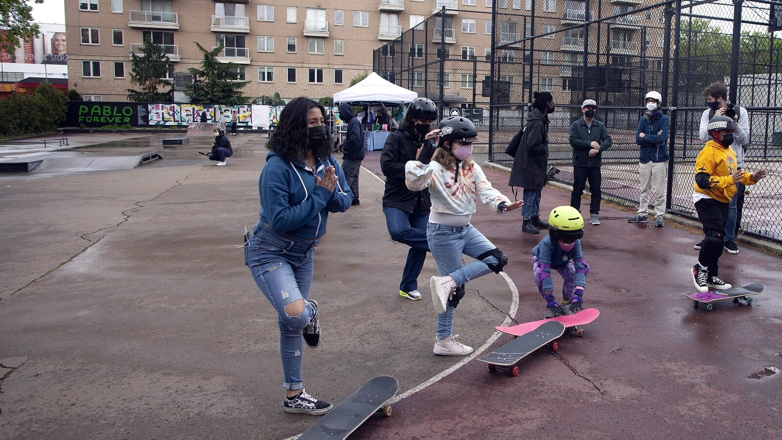 Groupe de débutants un pied sur la planche, l'autre au sol, pendant un cours pour apprendre à monter sur un skate