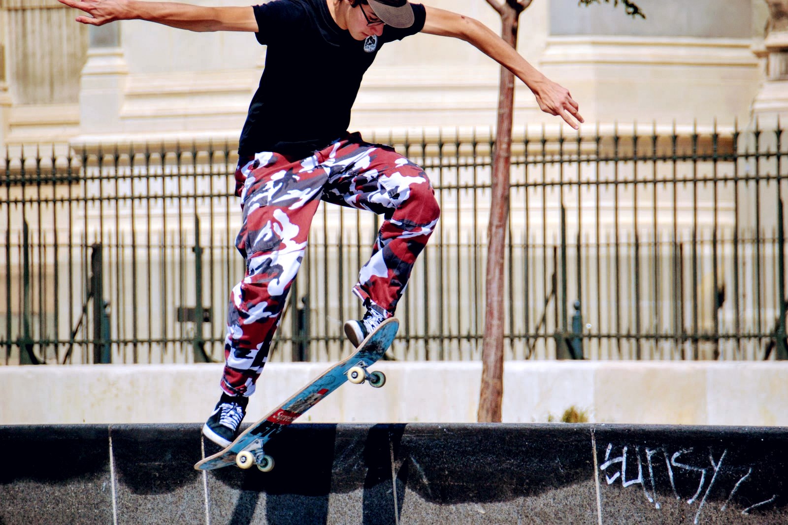 Skateur en boardslide sur un ledge en béton, bras écartés pour tenir la figure jusqu'au bout