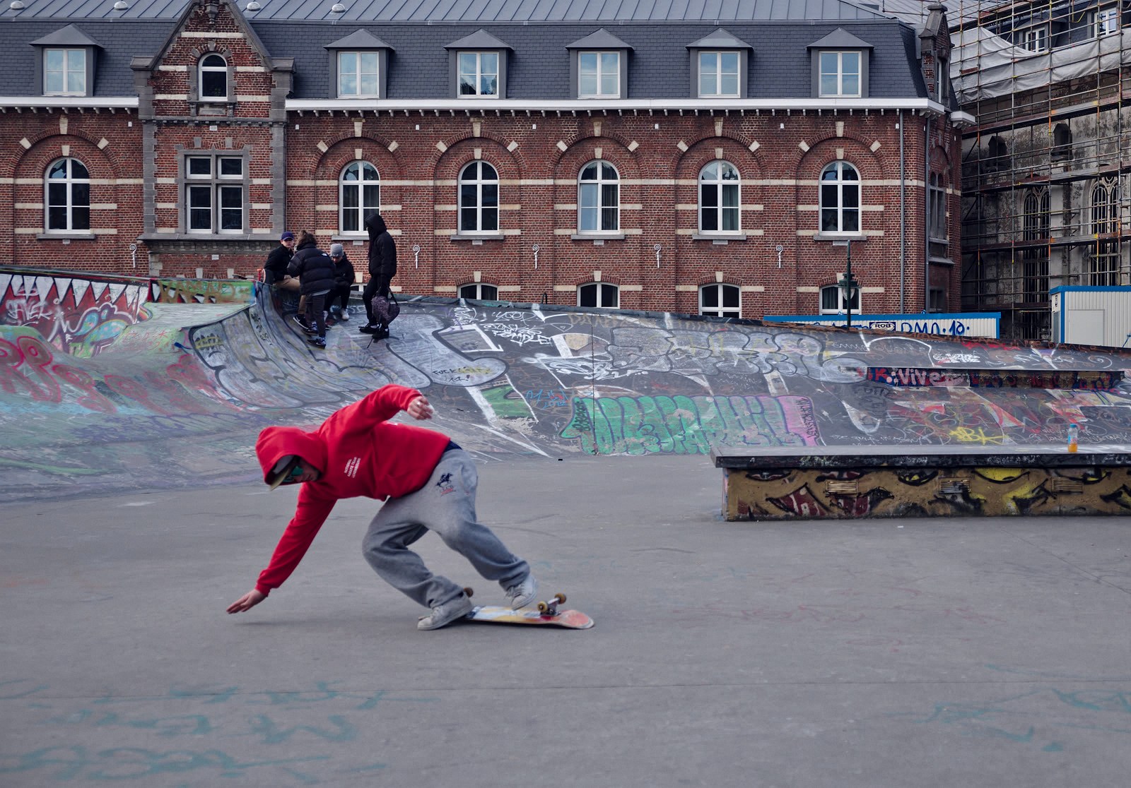 Skateur qui pose la main au sol après une réception ratée, planche partie devant lui sur le béton