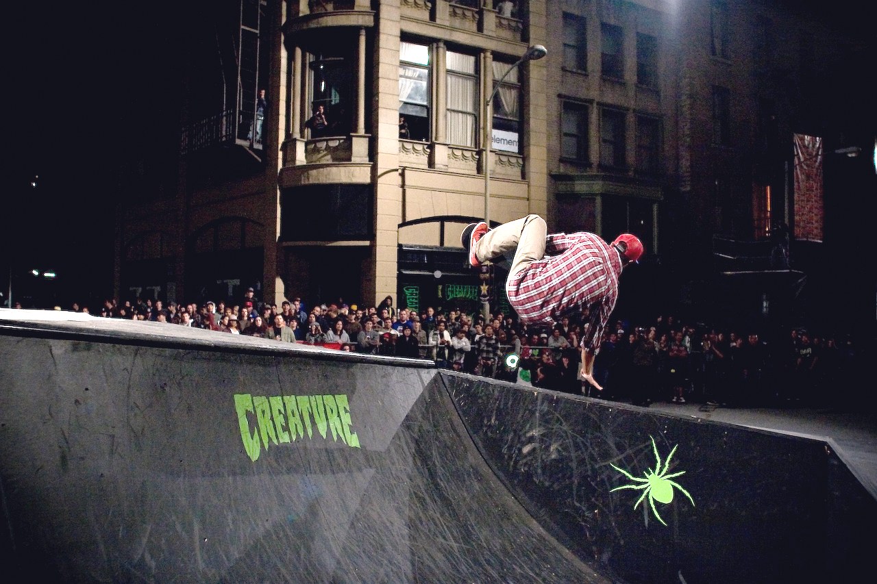 Eric Koston en l'air au-dessus de la rampe Creature du Vans Downtown Showdown en 2008, la foule massée derrière