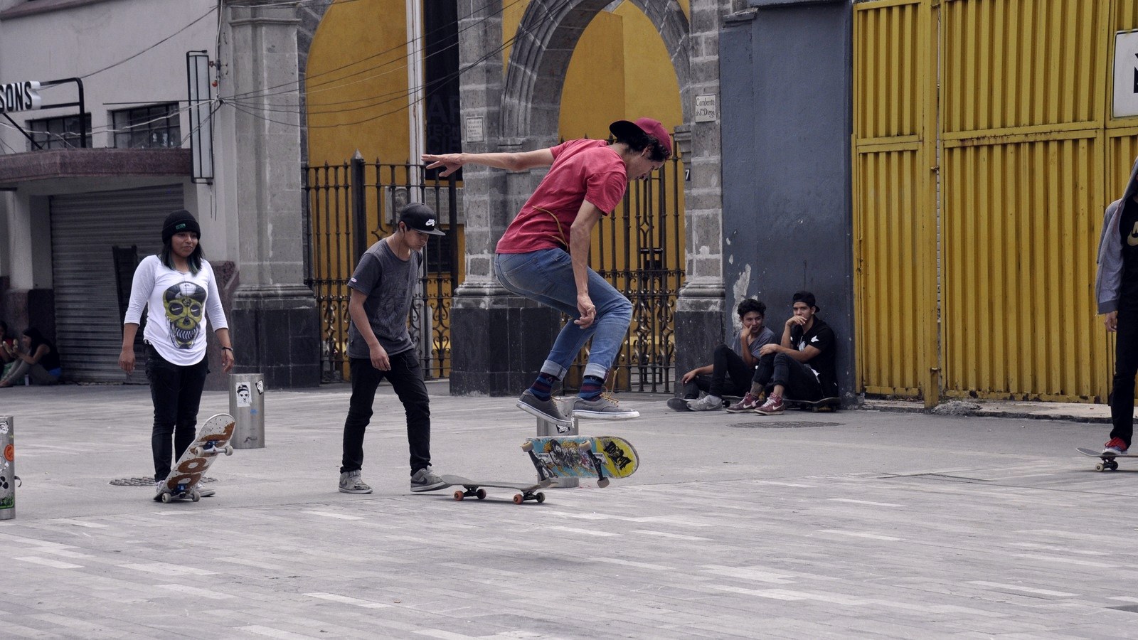 Skateur de rue au moment où la planche finit sa rotation sous ses pieds, entouré de son crew