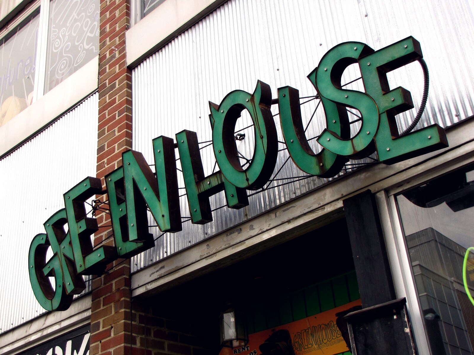 Enseigne du Greenhouse Boardshop vue d'en bas, au-dessus de l'entrée de la boutique