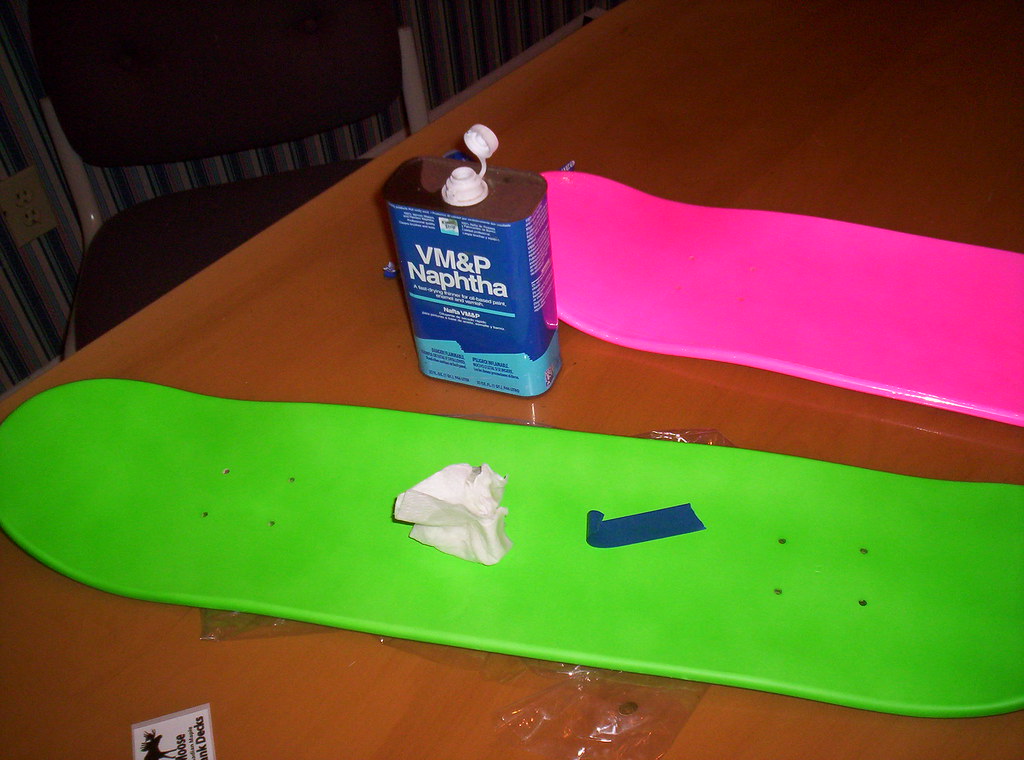 Deux decks de skate nus, un chiffon et un solvant sur la table avant de coller le grip