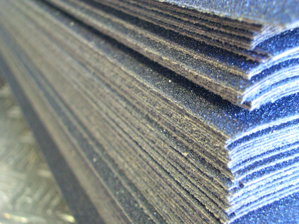 Pile de feuilles de grip tape noir avant la pose sur un deck de skate