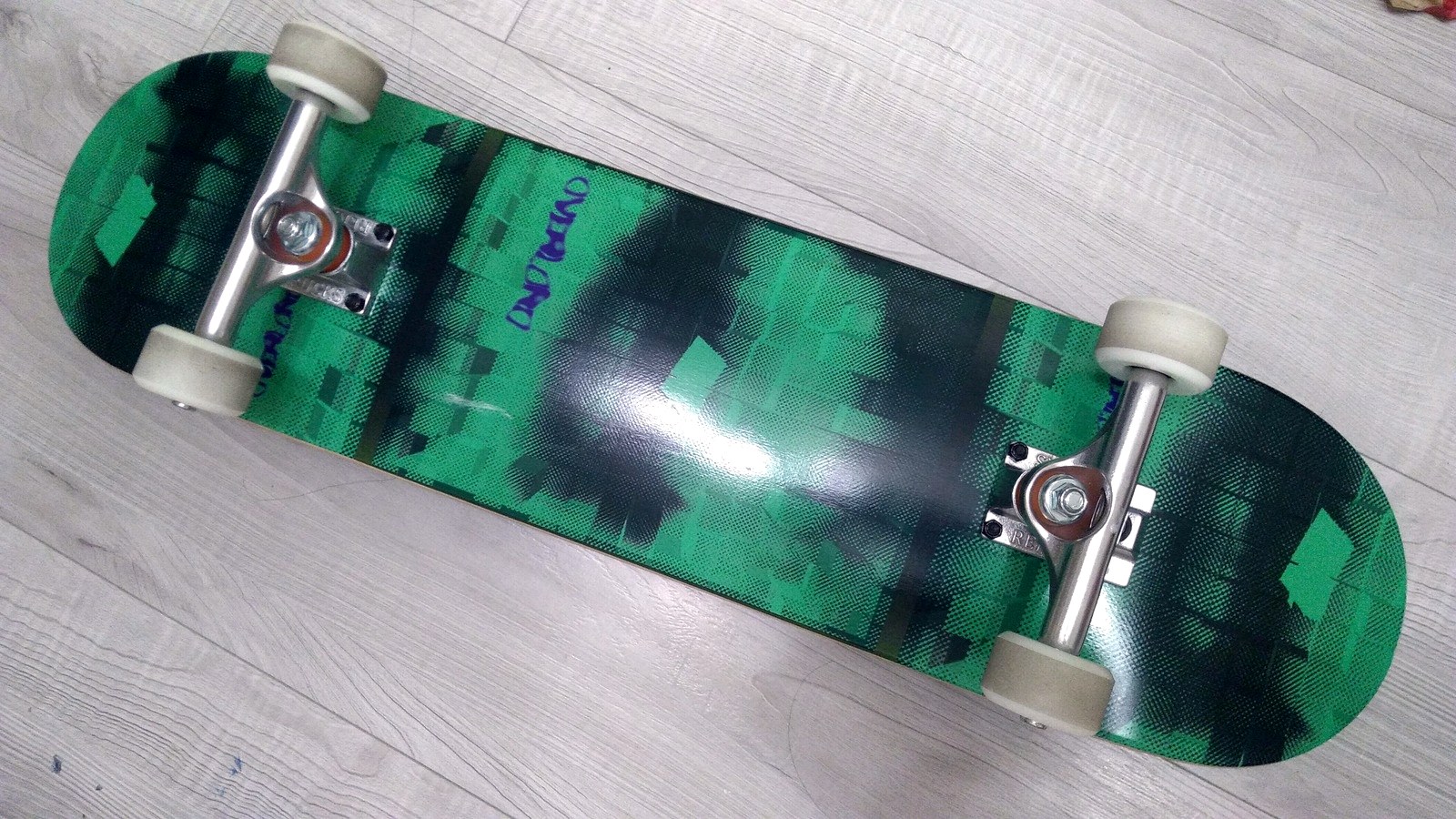 Dessous d'une planche de skate complète : tail, trucks et roues visibles