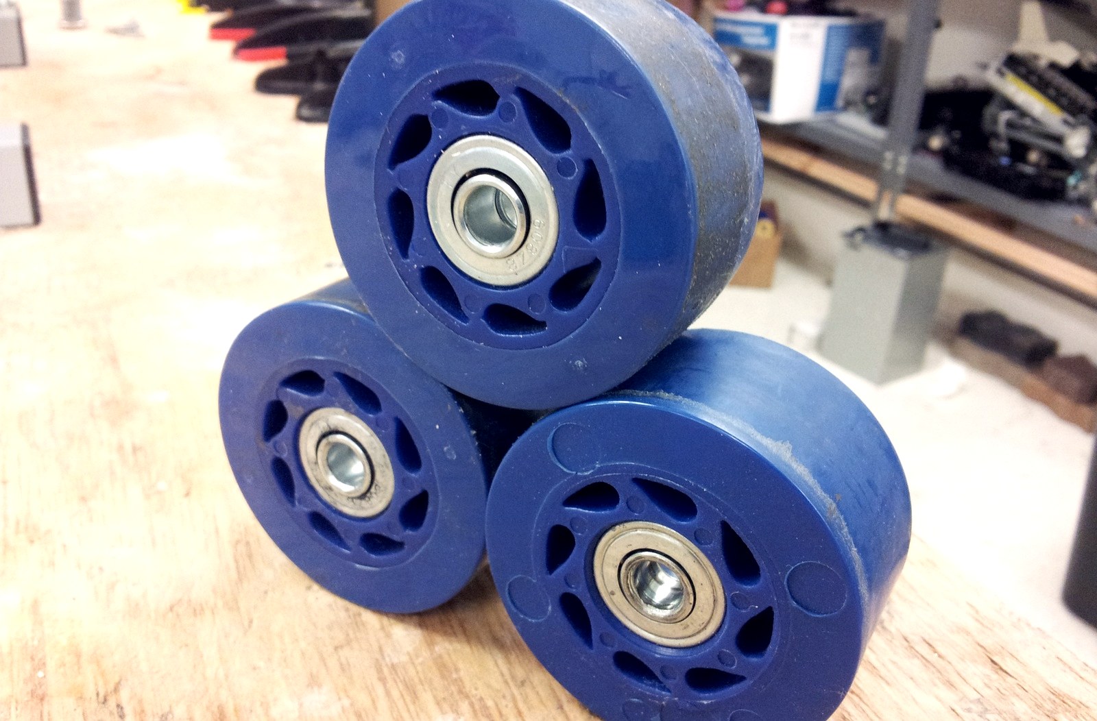 Trois roues de skate démontées posées sur un établi, roulements en acier apparents au centre
