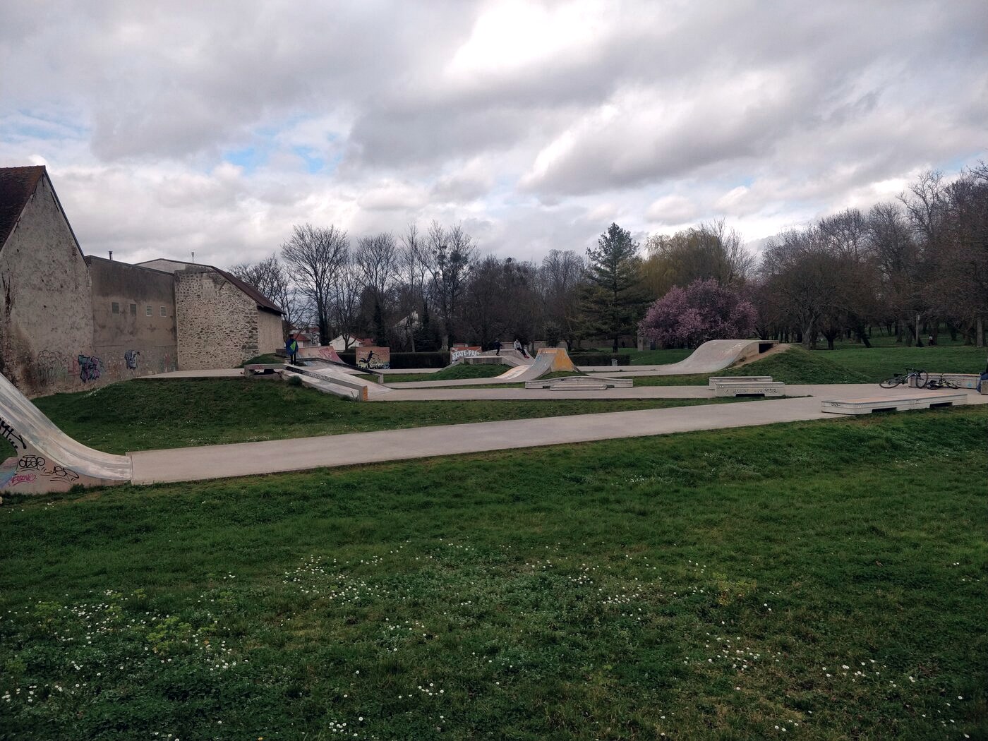 Skatepark en béton posé au milieu d'un espace vert de périphérie, entièrement désert un après-midi de semaine