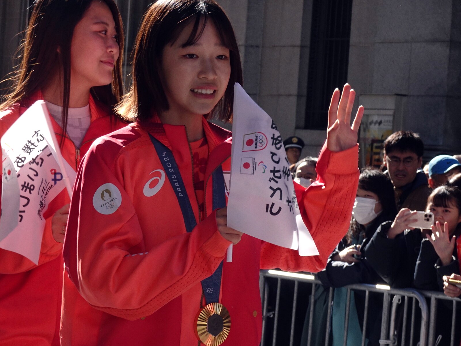 Coco Yoshizawa, médaille d'or de Paris 2024 autour du cou, saluant la foule lors du défilé de l'équipe du Japon