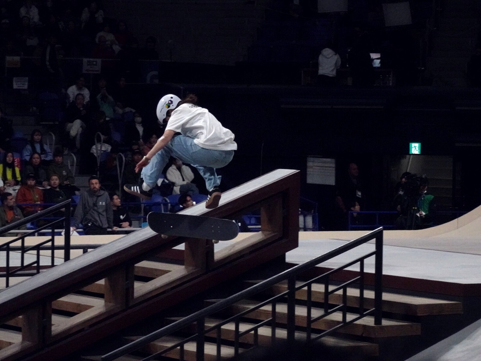 Skateuse en l'air au-dessus d'un rail, planche retournée sous les pieds pendant un best trick