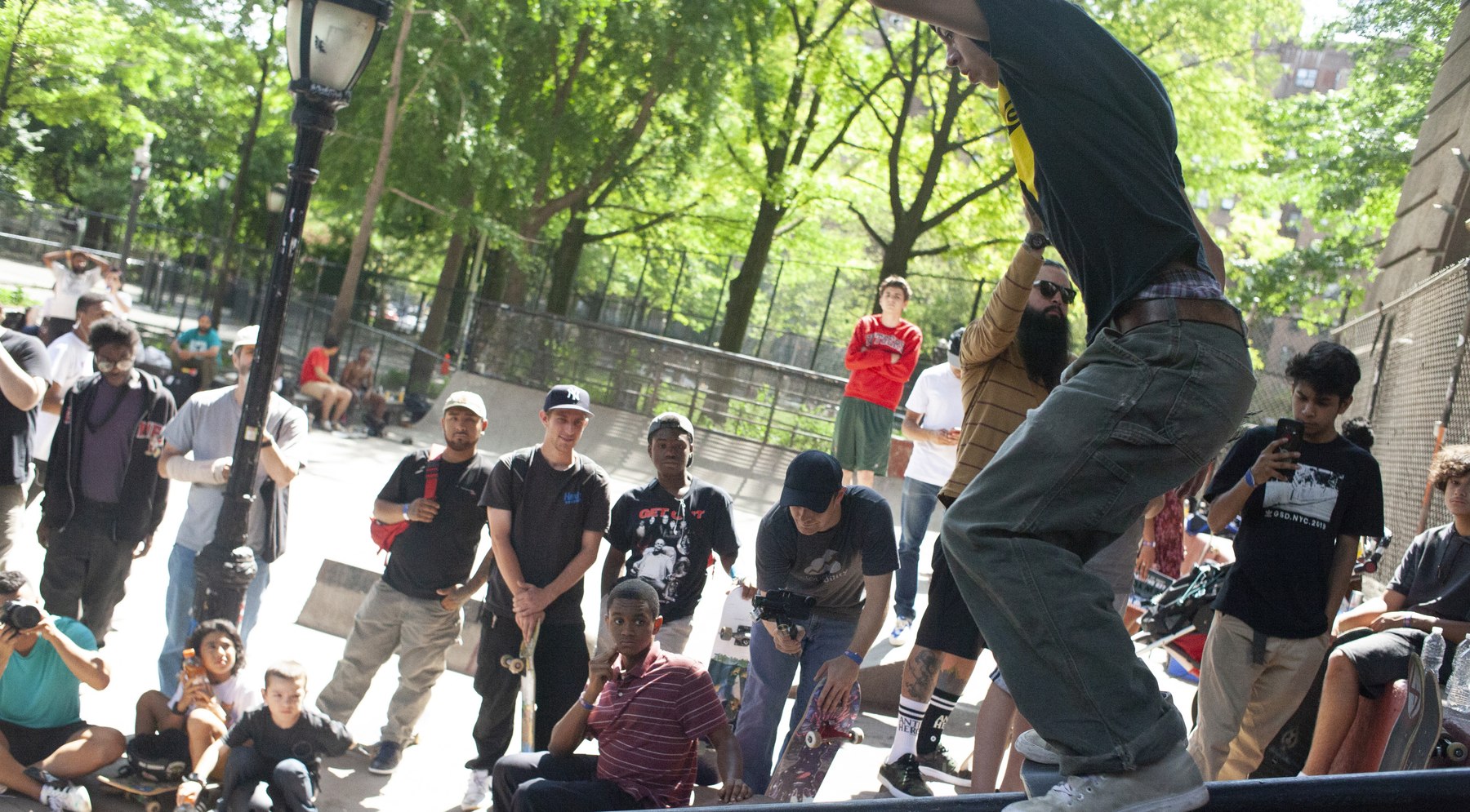 Un boardslide sur rail en contest street, foule massée autour de l'obstacle — l'ambiance d'une finale street