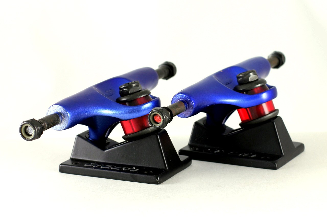 Trucks de skate vus de profil, les deux bushings rouges empilées autour du kingpin qui règlent le serrage