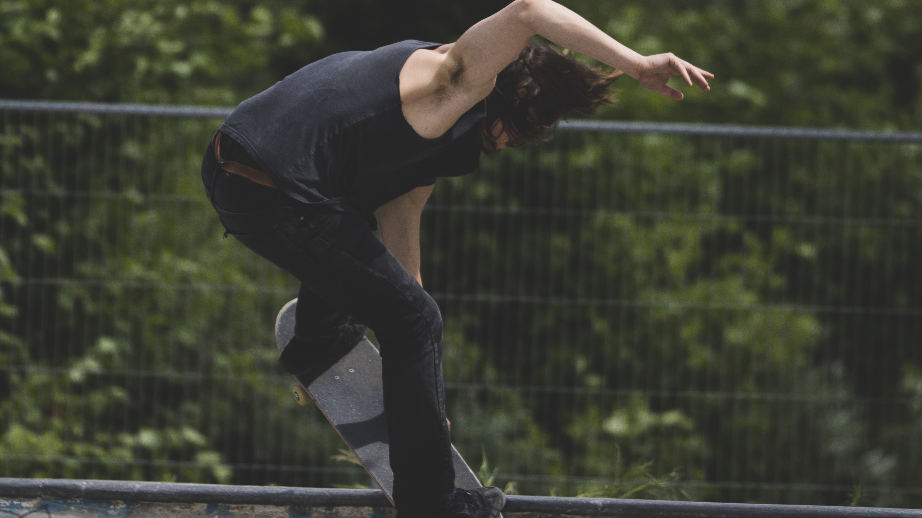 Skateur en action sur le coping du Dog Shit Spot à Berlin, grillage et végétation derrière