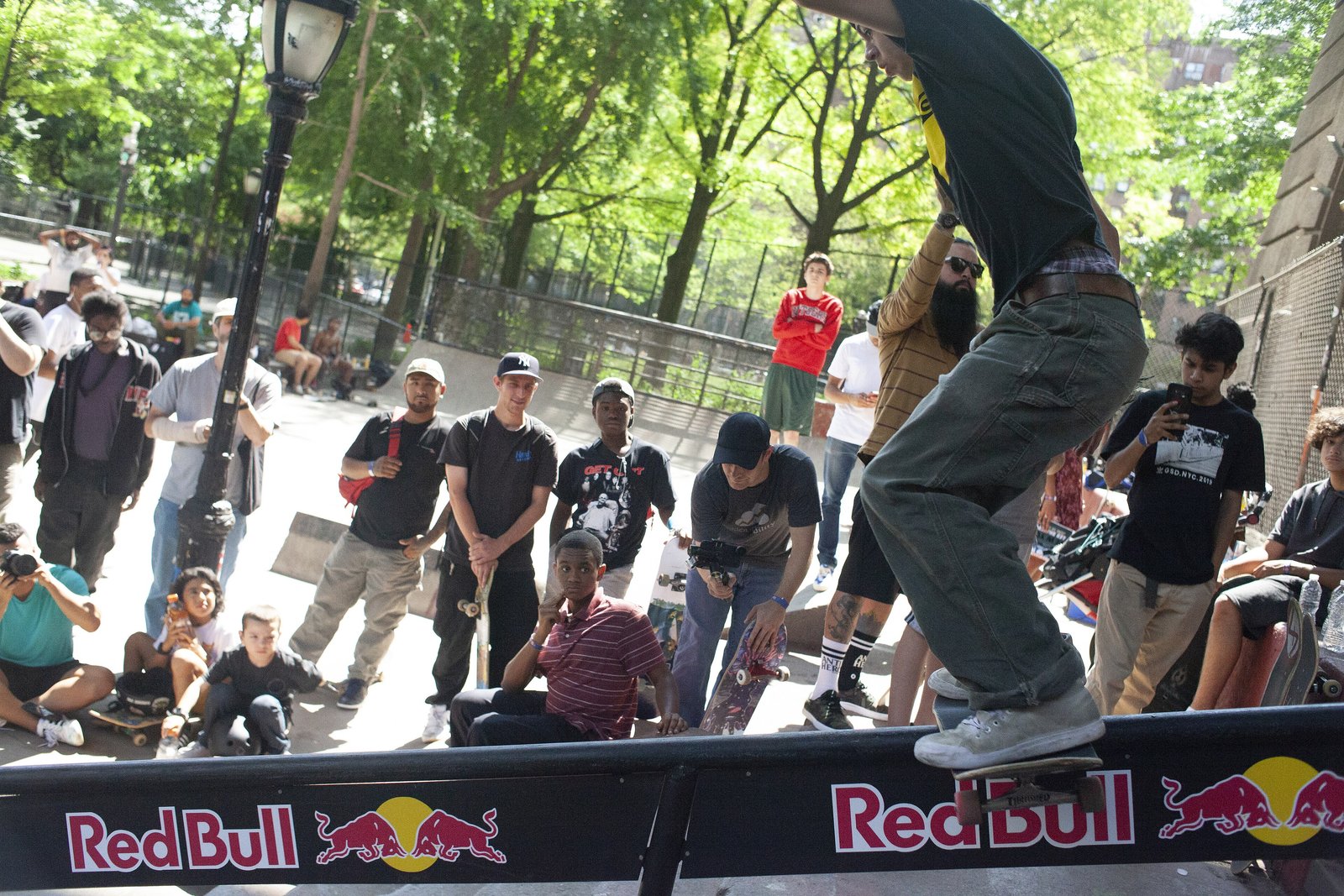 Boardslide sur une flatbar basse au skatepark LES de New York : la planche en travers de la barre, le poids posé au-dessus