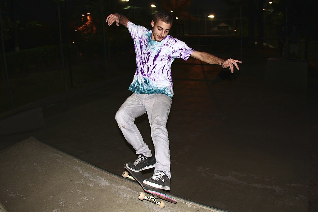 Frontside feeble grind sur un ledge de skatepark la nuit, bras ouverts, board en travers qui ne pivote pas