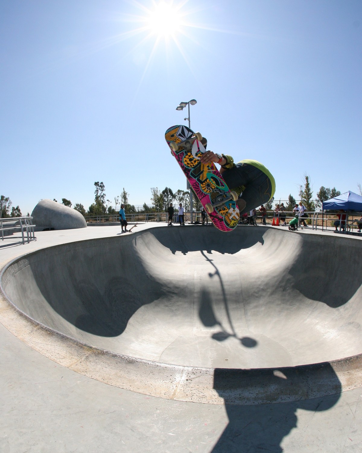 Lyn-Z Adams Hawkins en backside air au-dessus d'un bowl en béton en 2009, planche Birdhouse et sticker Volcom