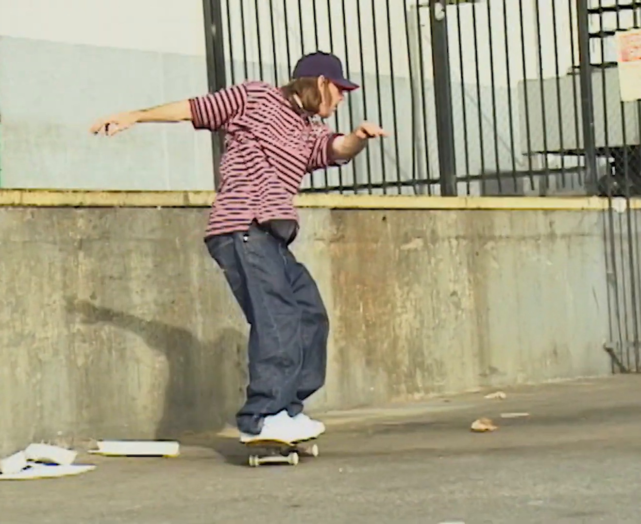 Tom Penny en polo rayé et jean large, en équilibre sur sa planche le long d&rsquo;un mur, partie Flip Extremely Sorry (2009)