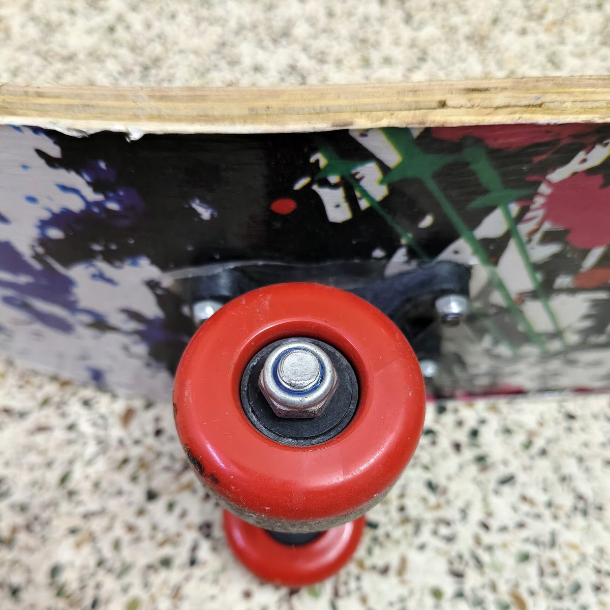 Tranche d'un plateau de skate abîmé où l'on voit les couches de bois collées, la zone que l'eau attaque sous la pluie