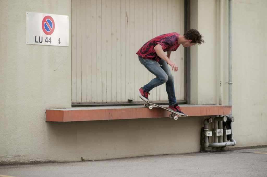 Backside Smith grind sur un ledge de quai : le buste penché au-dessus du ledge, le nose qui plonge