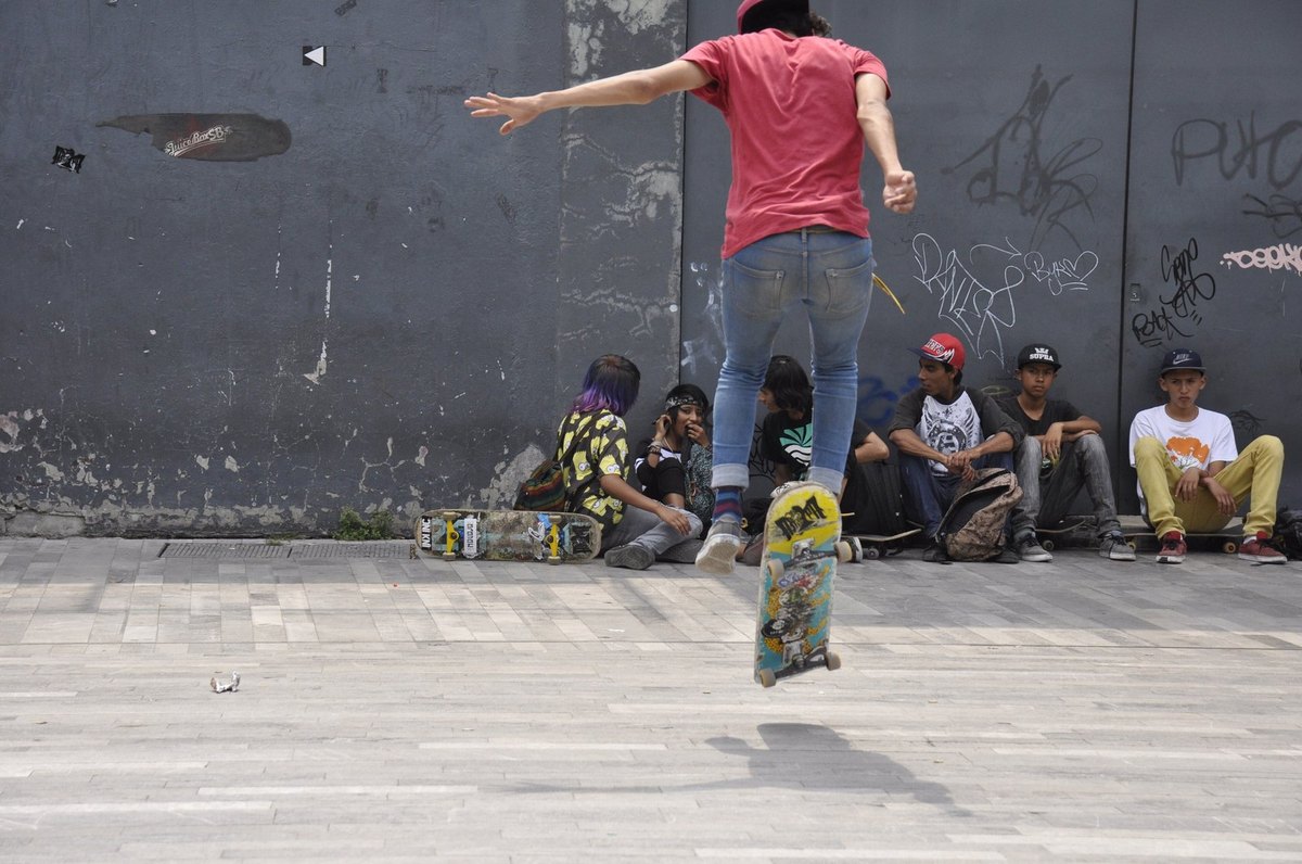 Fail du varial kickflip : la planche part sur la tranche, loin des pieds du skateur, au milieu d'une session de rue
